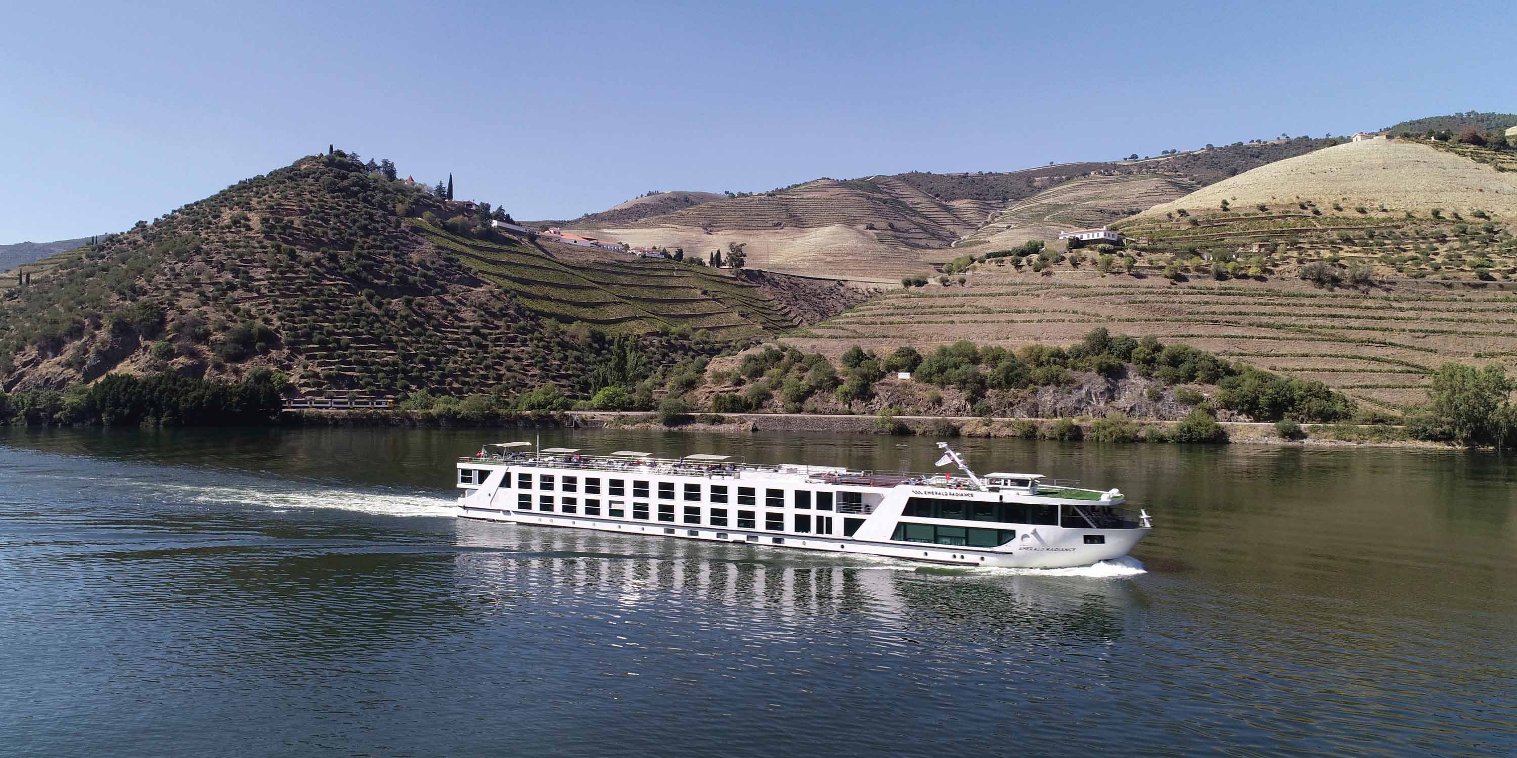 a river ship passing by on the river with hills behind it