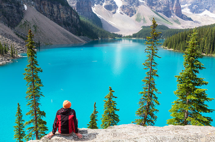 Man looking over bright blue lake in Canada