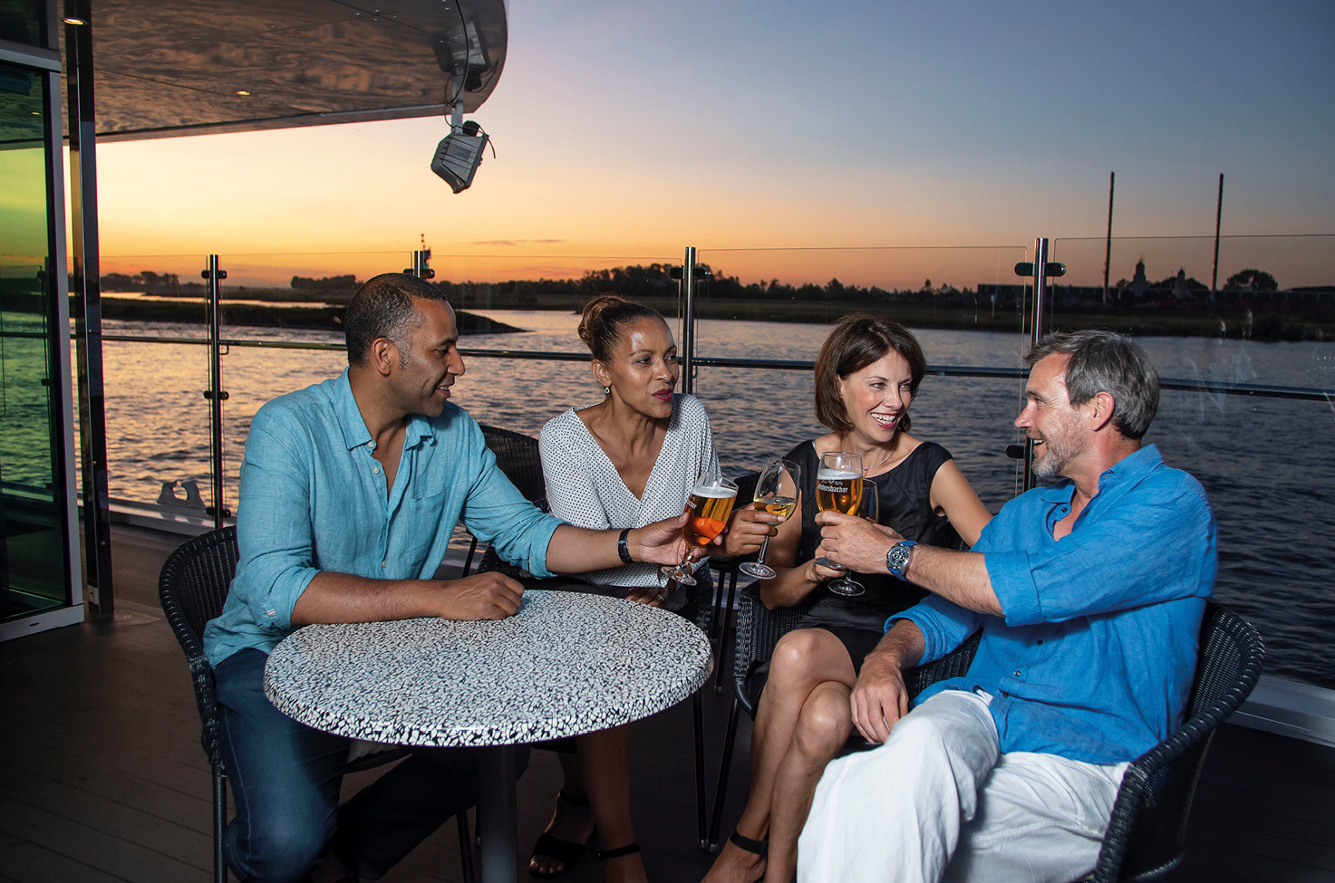 Four cruise guests enjoying a drink as the sun sets