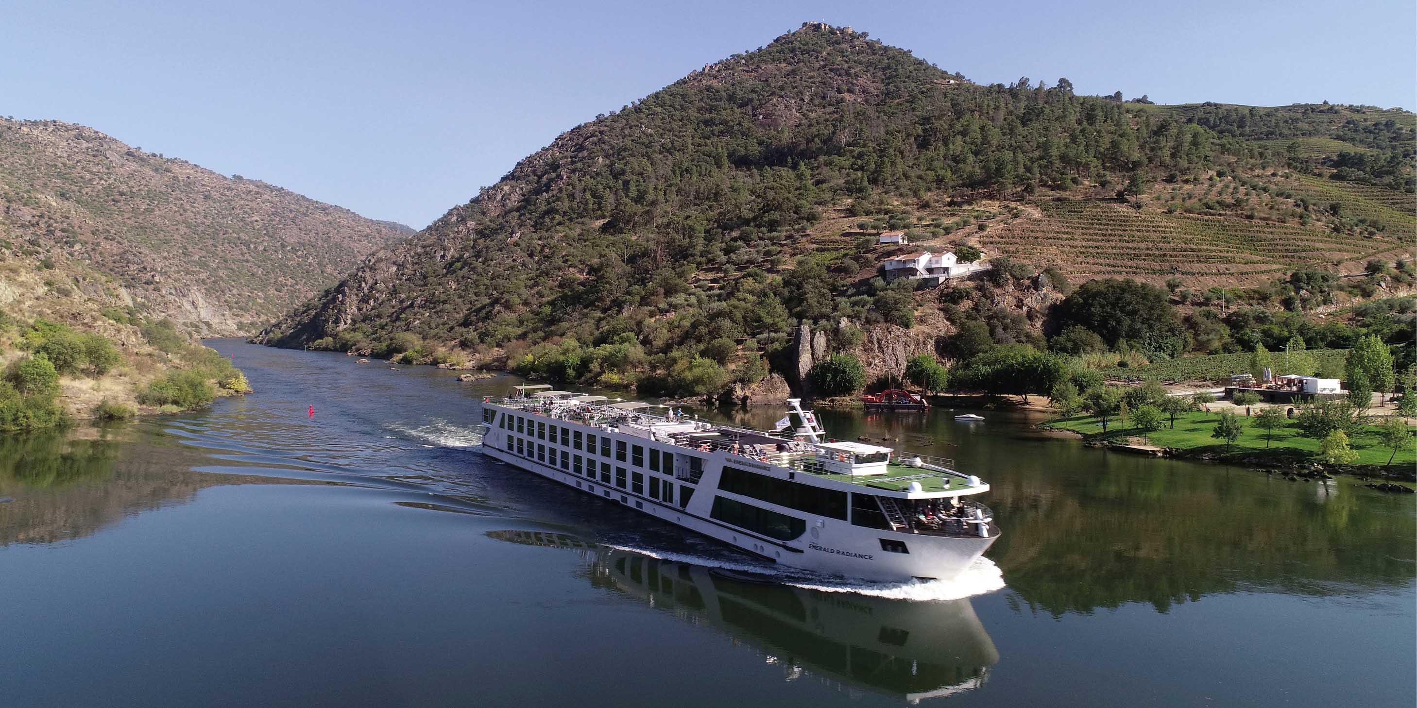 The Emerald-Radiance Star-Ship sails through Portugal’s Douro Valley, backed by green rolling hills. 
