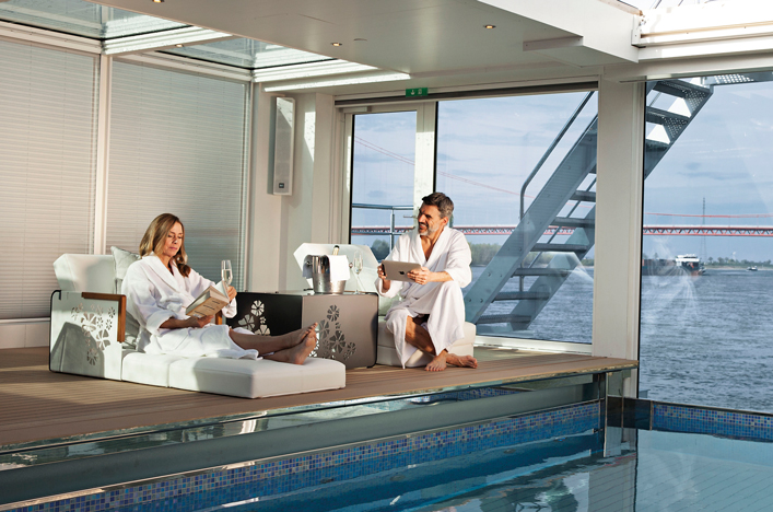 Couple reading and relaxing next to pool on board river cruise