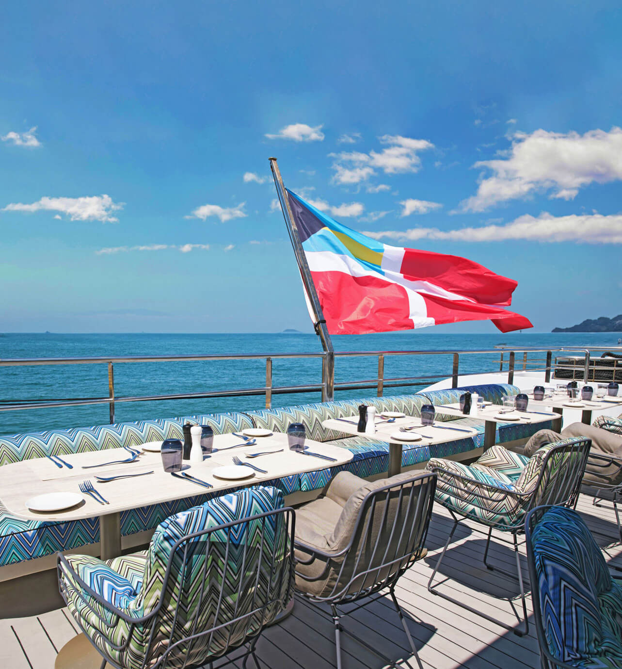 Flag at the Stern of cruise ship with tables and chairs set for dining.