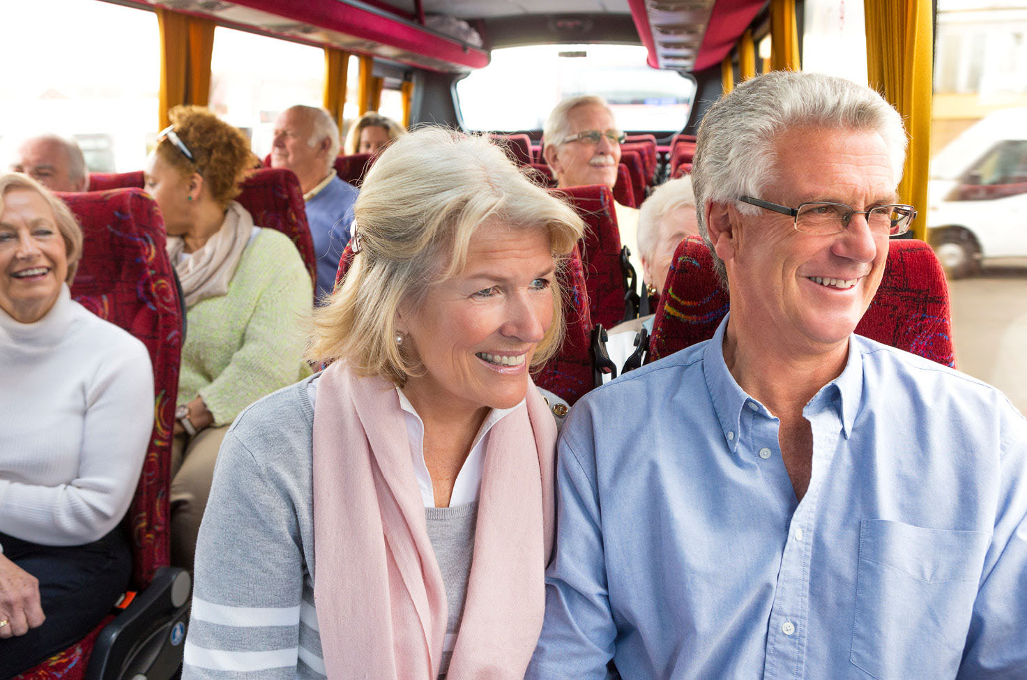 A group of coach passengers smiling and looking out of the window