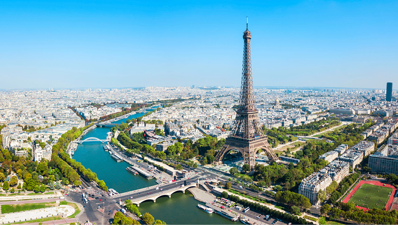 Aerial view of Paris, with the Eiffel Tower and River Seine in clear view, a blue sky above