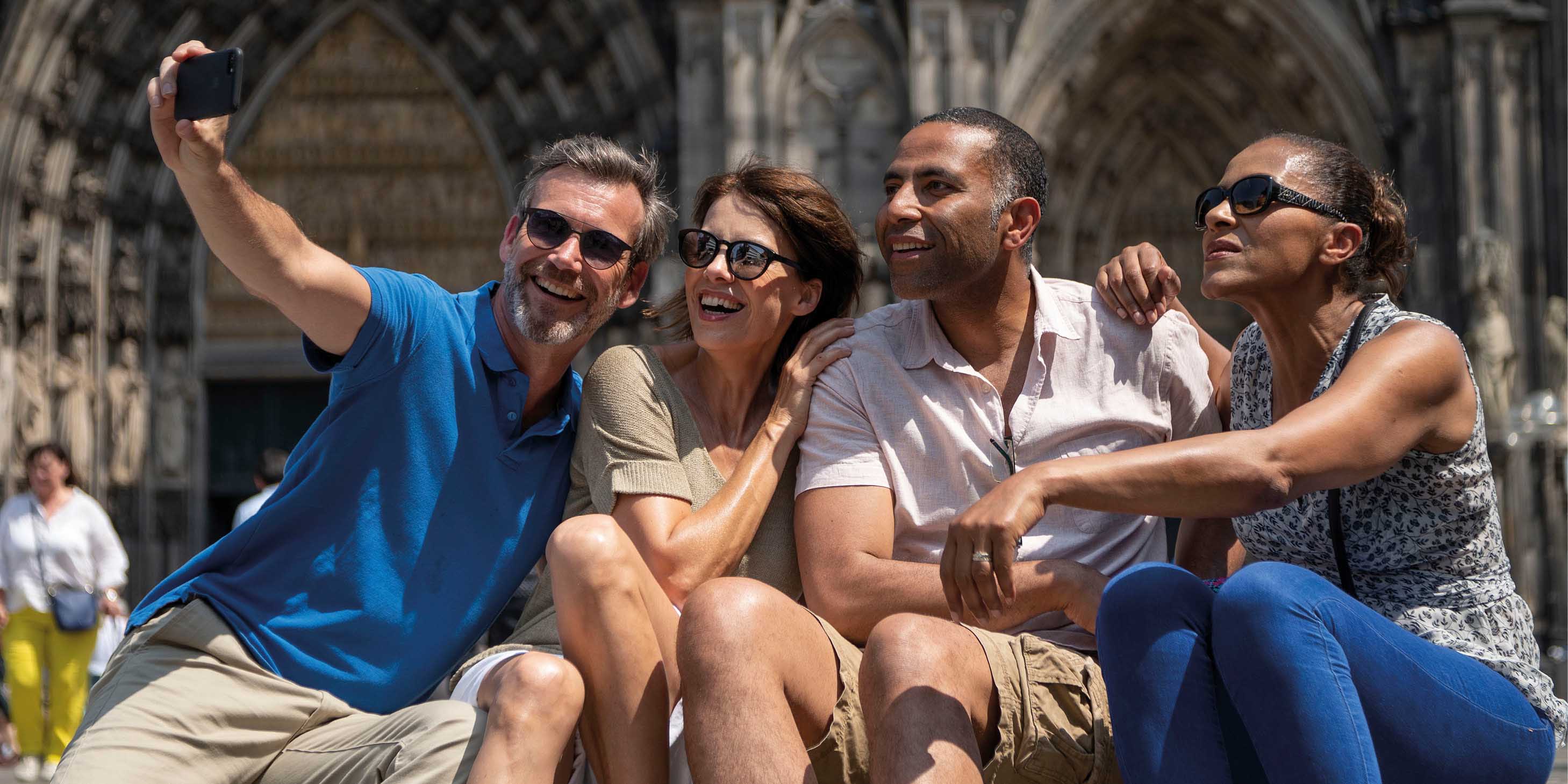 A group of four friends taking a selfie outside of Cologne Cathedral in Germany