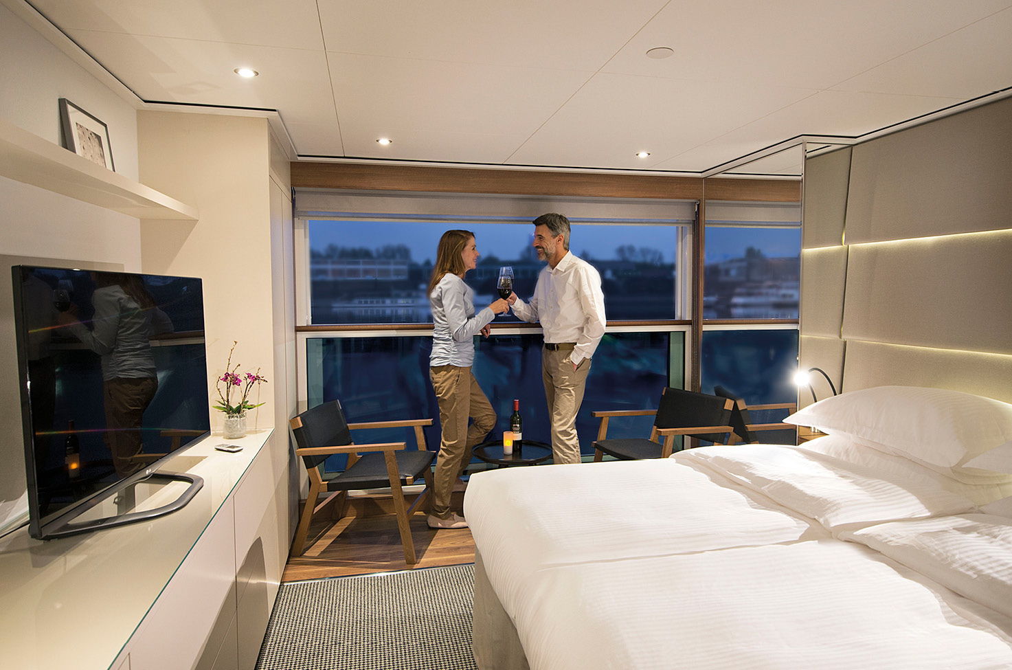 Guests enjoying a glass of wine at the balcony of their suite on board a luxury river cruise
