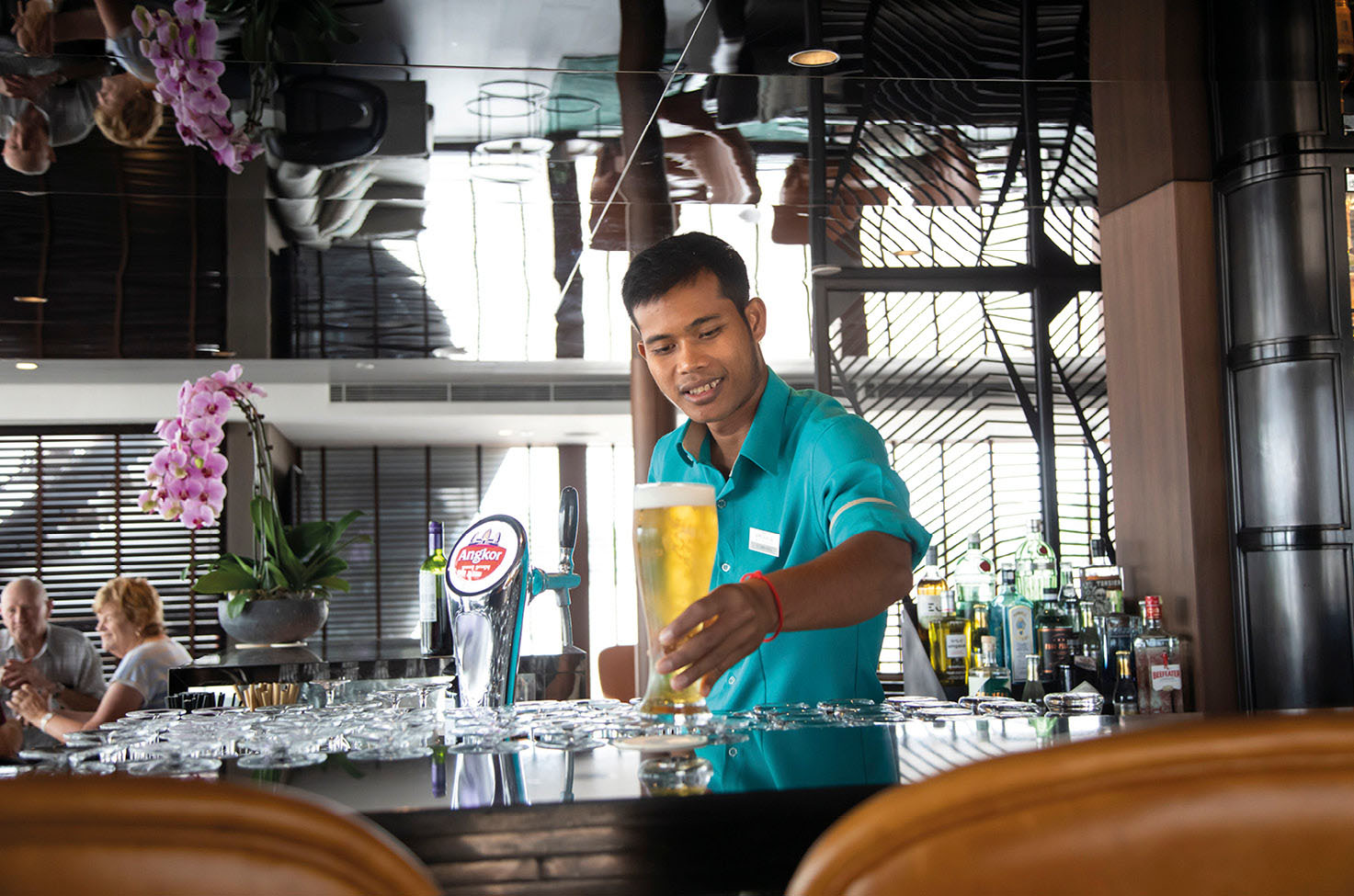 Bartender serving a crisp cold beer on board a luxury river ship on the Mekong River in Southeast Asia