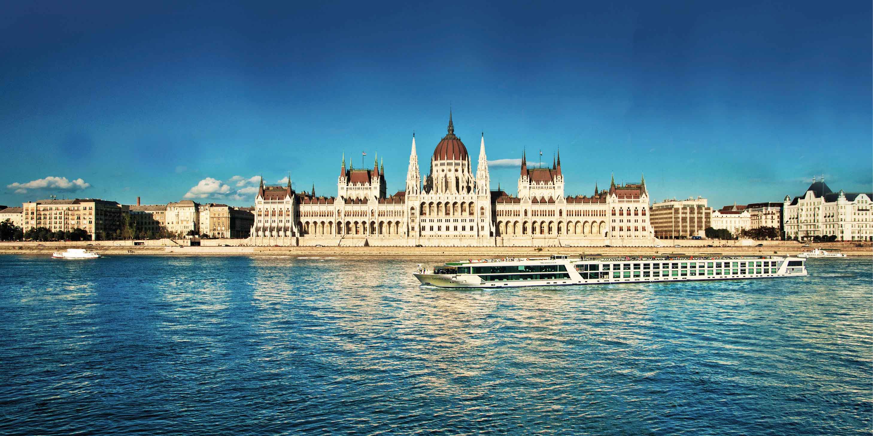 An Emerald Cruises luxury river ship sailing down the Danube in Budapest in front of the Parliament building