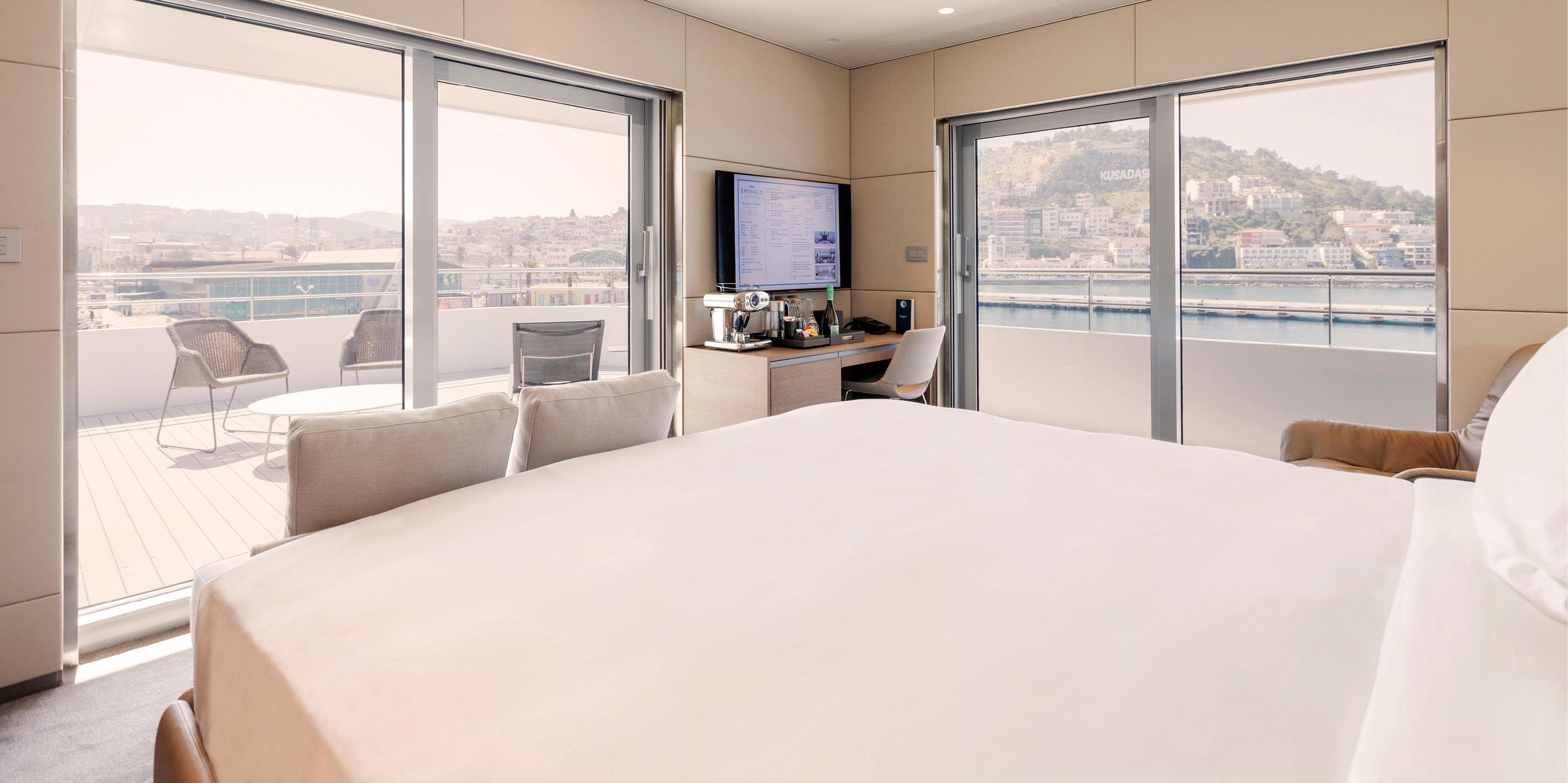 A large cabin on an Emerald Cruises yacht with comfortable bed facing an incredible view out across the terrace and balcony