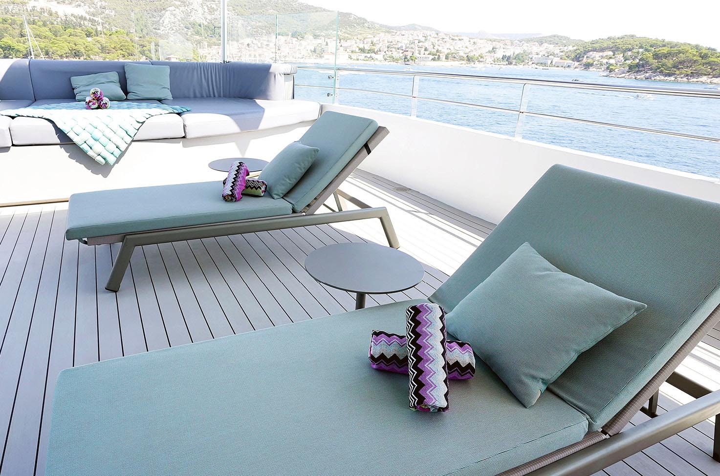 Two sun loungers and a separate seating space set up on deck, with a city in the background