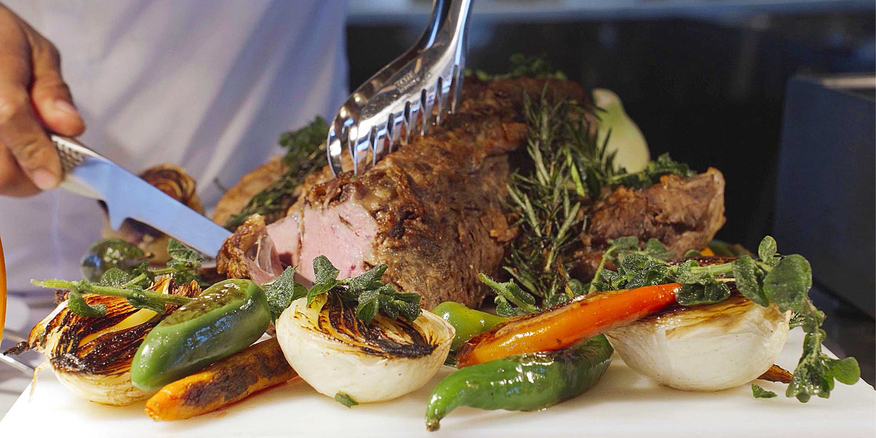 Chef cutting delicious meat surrounded by fresh local produce for guests on board an Emerald Cruises luxury yacht cruise